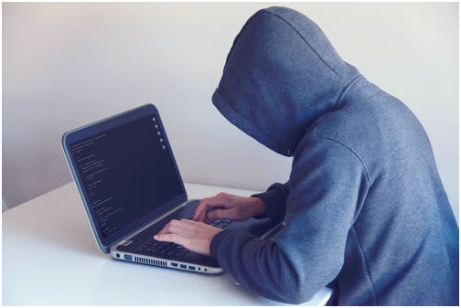 Anonymous hacker on a laptop in a white room