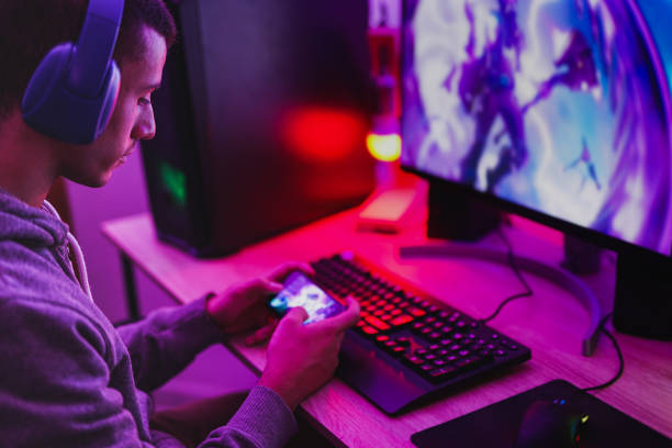 A person gaming on a computer and mobile phone